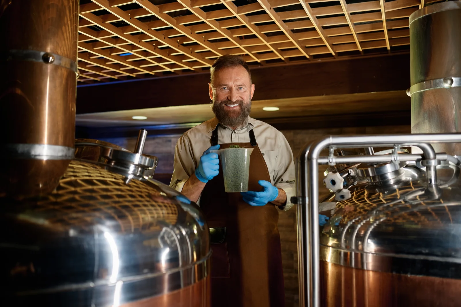 smiling maturebrewer-holding plastic glass with granulated malt